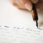 A picture of someone with a fountain pen writing a letter.